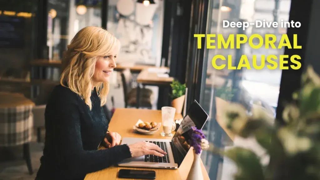 A smiling woman in a cozy cafe working on a laptop, taking a deep-dive into temporal clauses in German grammar.
