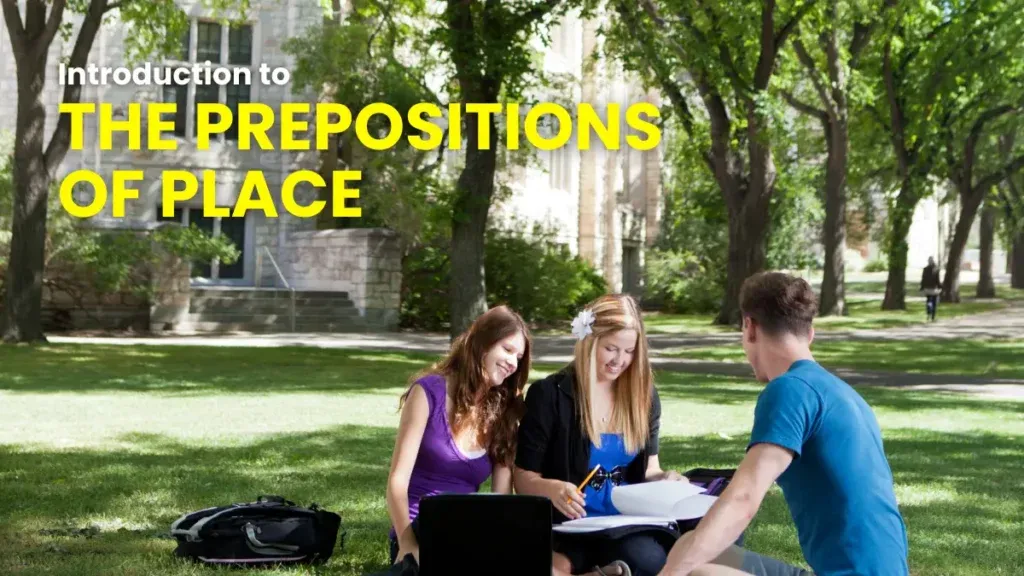 Three students sitting on the grass in a shaded college courtyard, engaging in a study session on the prepositions of place in German.