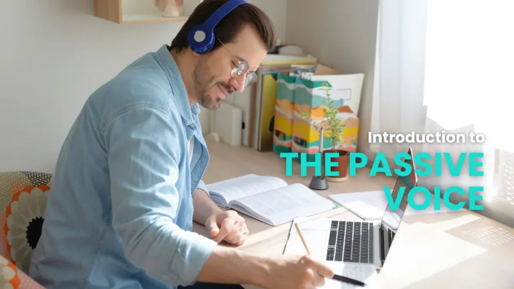 A man in a light blue shirt and headphones concentrating on his laptop, learning about the passive voice in German.