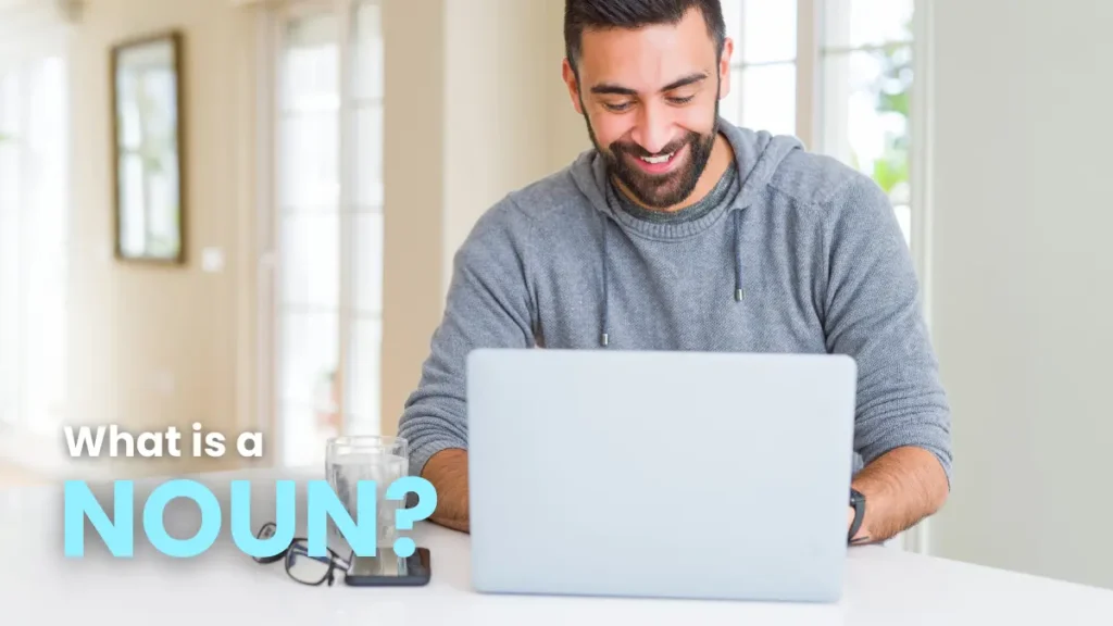 Man smiling at a laptop, learning about nouns in German grammar.